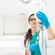A healthcare professional from Boss Infusions, wearing blue gloves and a stethoscope, adjusts an IV drip in a bright, clean medical setting—delivering expert IV Infusion Therapy Brisbane can trust.